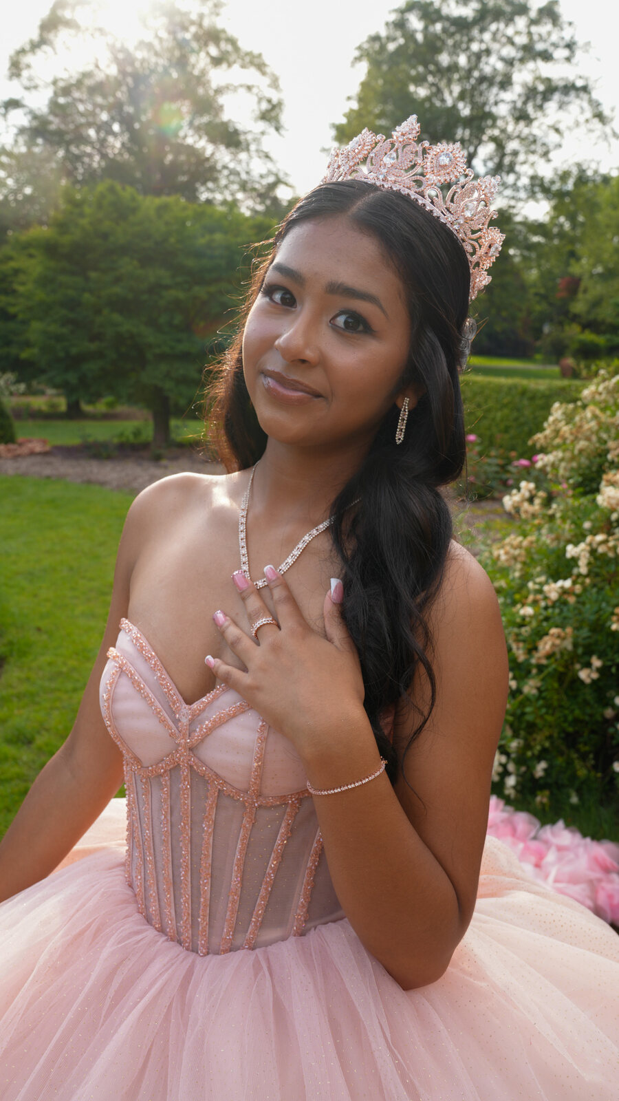 Close portrait of a quinceañera wearing a tiara with her hand near her necklace