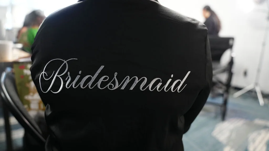 White script embroidery on a black satin Bridesmaid robe — wedding-morning detail, New Jersey