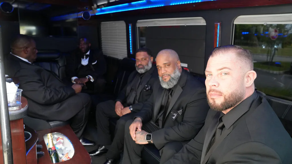Groomsmen ride to the ceremony under the party bus's blue lights — documentary wedding photography, New Jersey