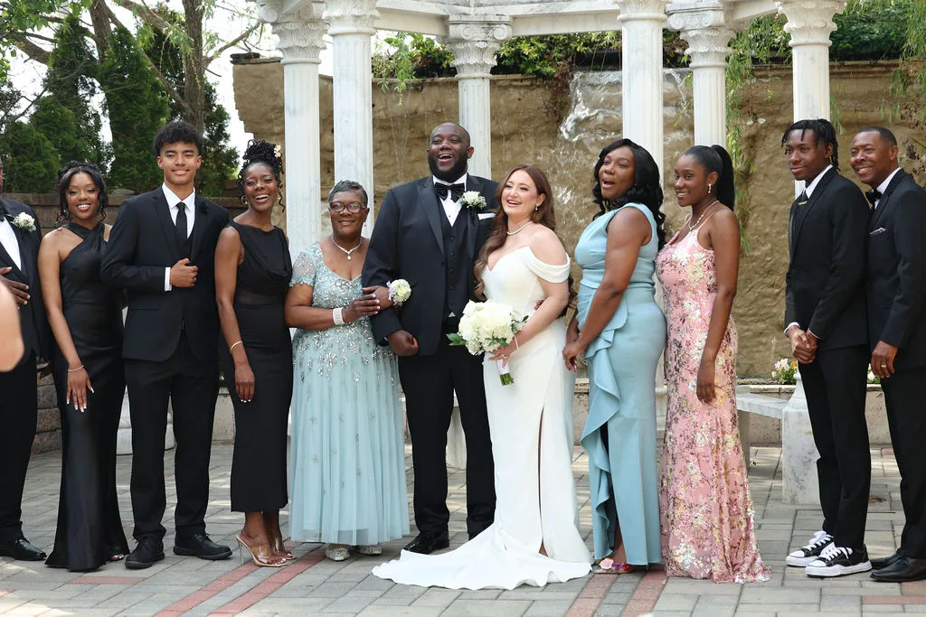 Becky and Tre laugh mid-portrait with family in the venue courtyard — joyful formal photography by Maximus Visions, New Jersey