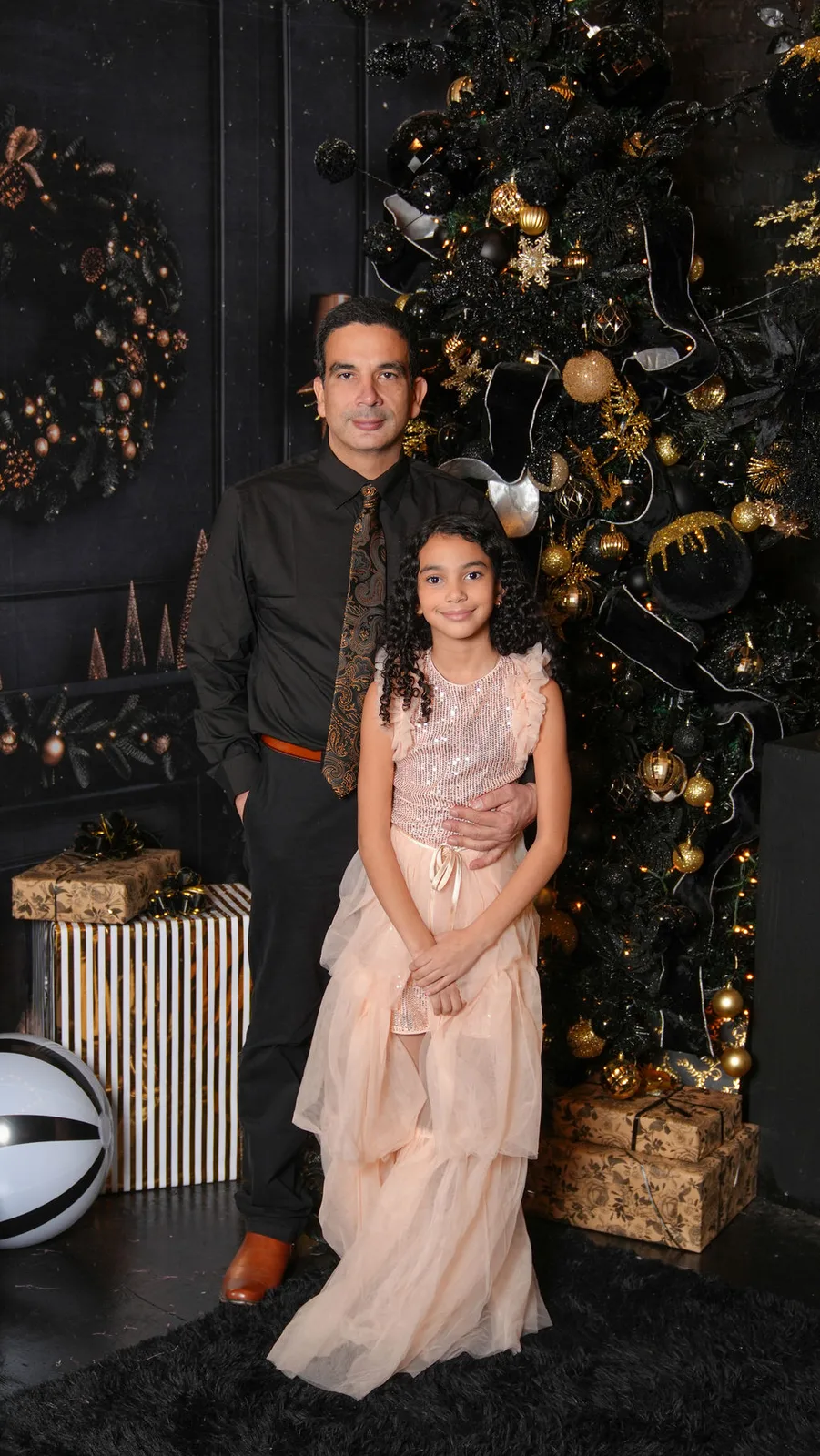Father and daughter in front of the black-and-gold tree, her sequin dress catching the light — Christmas portraits by Maximus Visions, New Jersey