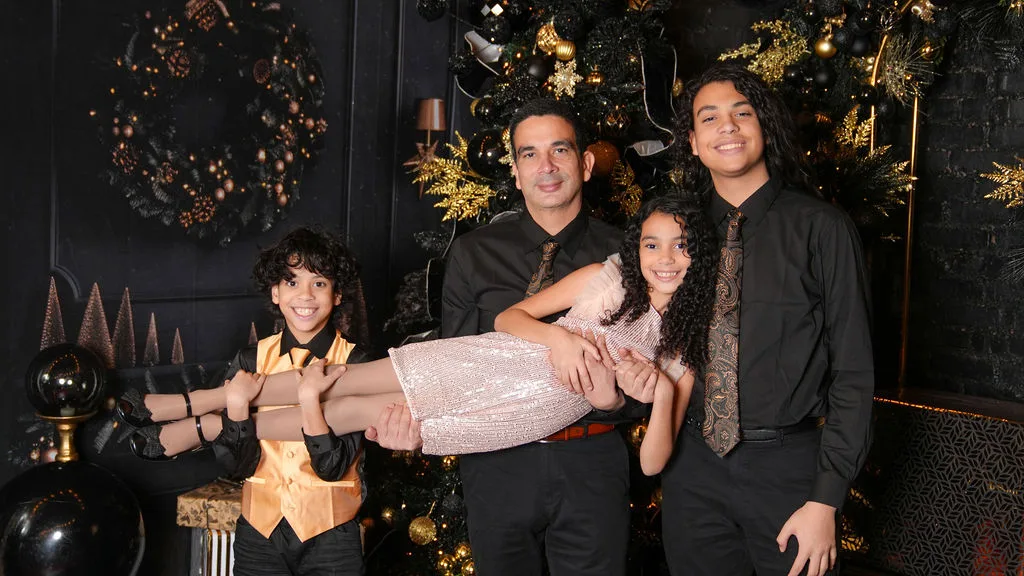 Dad and brothers playfully lift the youngest daughter during a studio family session — candid family portrait by Maximus Visions, New Jersey & New York City