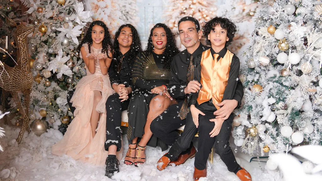 The Marlin family of five together under falling snow on the white winter set — Christmas portraits by Maximus Visions, New Jersey