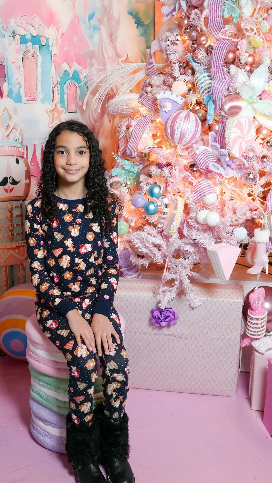 The youngest Marlin seated on a giant macaron in the pastel candyland set, pink tree glowing behind her — Maximus Visions, New Jersey
