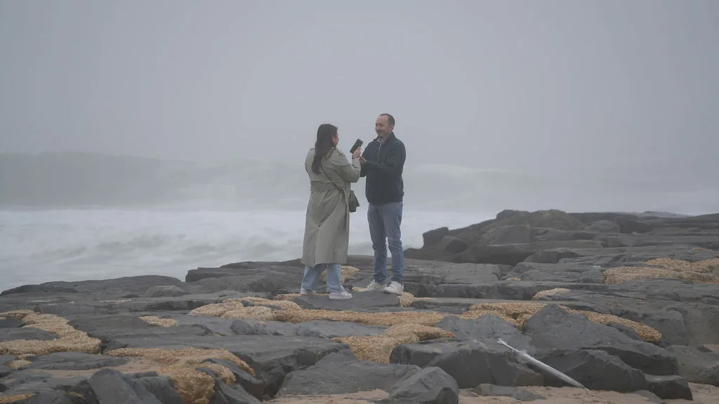 A quiet conversation out on the jetty, the ocean grey and endless behind them — New Jersey proposal session