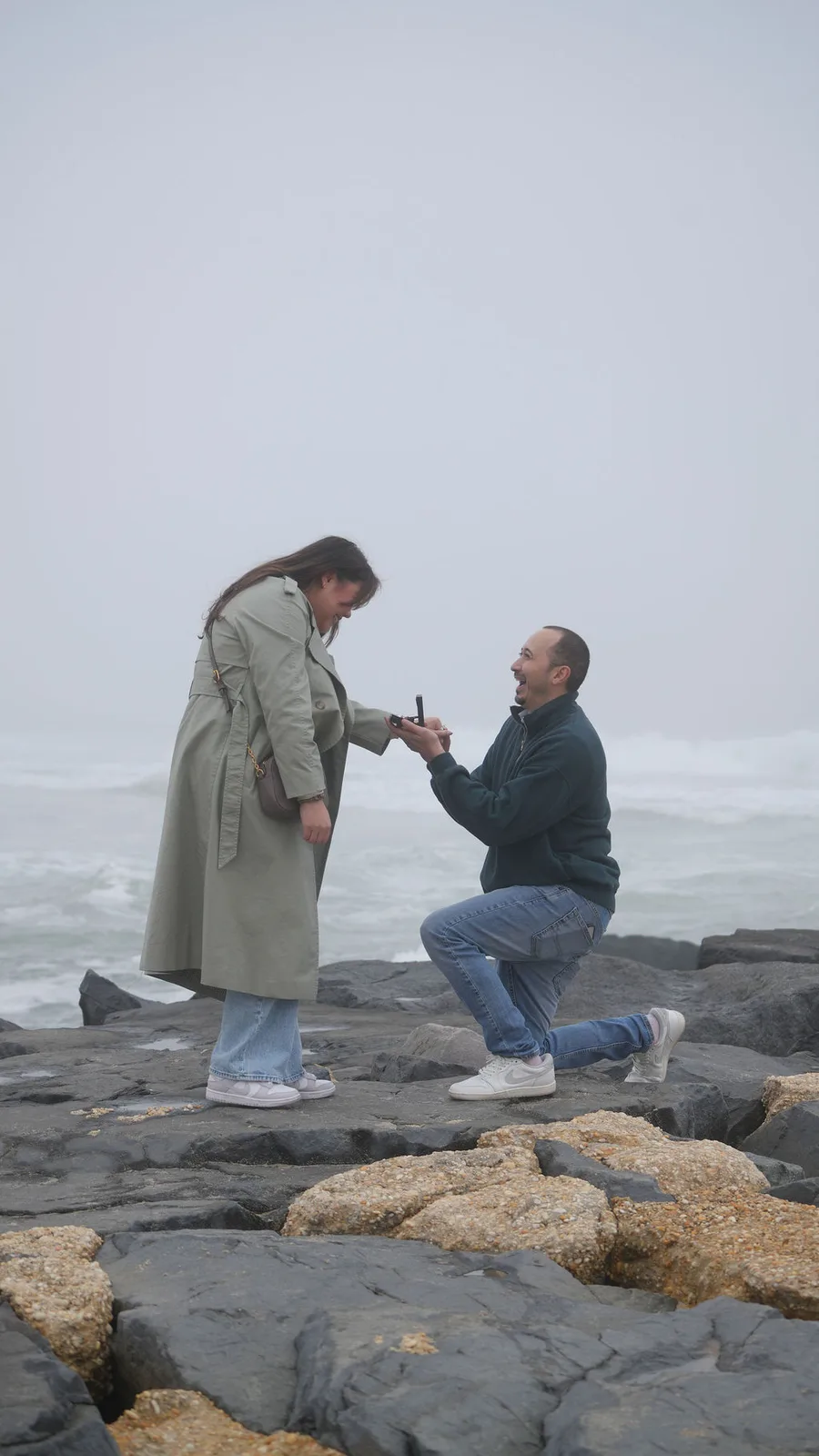 The ring box open in his hands as he kneels before her on the rocks — proposal detail, New Jersey