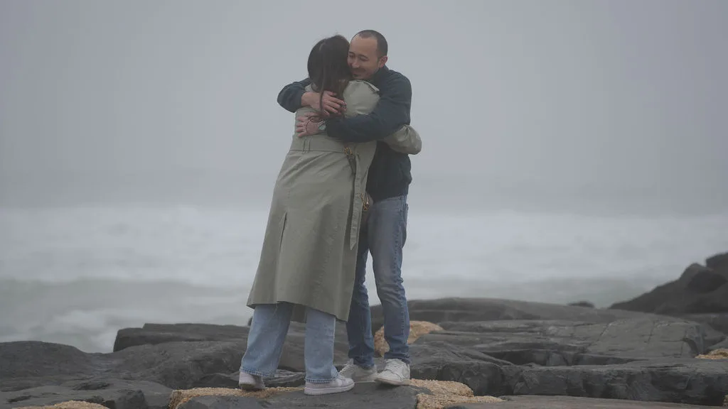 A quiet embrace as the news settles in, waves breaking below the rocks — New Jersey proposal photography